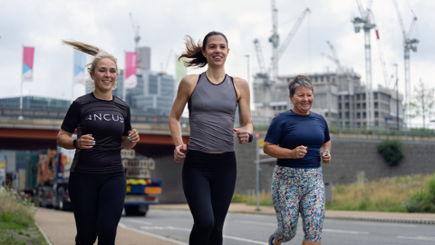 3 women in branded INCUS clothing running along a road.